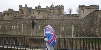 Turistas con paraguas decorados con la bandera brit&aacute;nica, en los alrededores de la Torre de Londres.