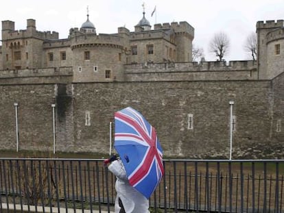 Turistas con paraguas decorados con la bandera brit&aacute;nica, en los alrededores de la Torre de Londres.