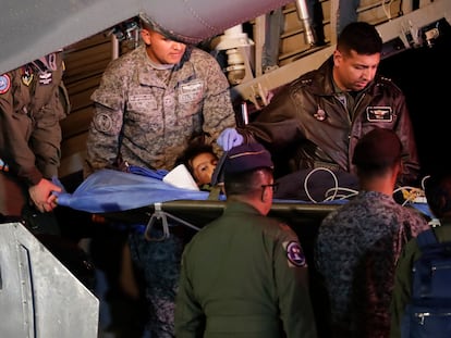 Personal militar traslada a uno de los niños rescatados tras aterrizar este sábado en la base aérea de Bogotá.