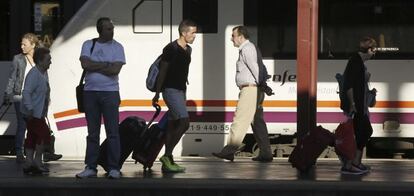 Varios pasajeros de tren con equipajes caminan por un and&eacute;n de la estaci&oacute;n de Chamart&iacute;n, en Madrid.  