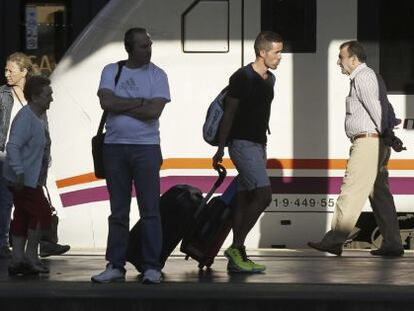 Varios pasajeros de tren con equipajes caminan por un and&eacute;n de la estaci&oacute;n de Chamart&iacute;n, en Madrid.  