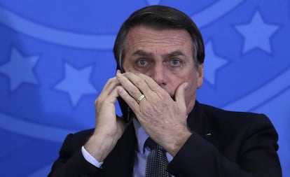 Jair Bolsonaro fala ao celular durante cerimônia no Palácio do Planalto.