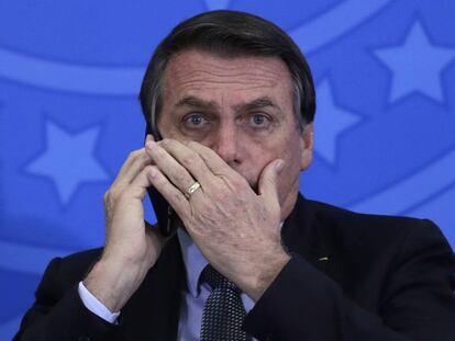 Jair Bolsonaro fala ao celular durante cerimônia no Palácio do Planalto.