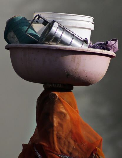 Retrato de una mujer india que vuelve a casa después de un día de trabajo en el campo. Es habitual que las mujeres transporten sus utensilios en la cabeza.