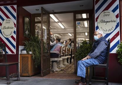 Un hombre, con mascarilla, espera en la barbería-peluquería El Kinze, en Cuchilleros, en el centro de Madrid, el 4 de mayo, primer día de apertura del comercio no esencial, que había estado cerrado por la epidemia de la covid-19.