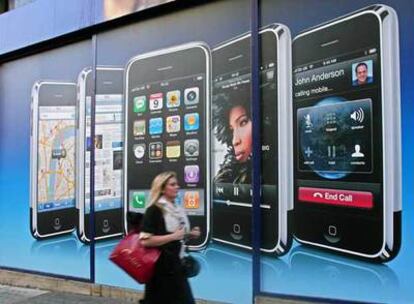 Una mujer pasea por una calle de Londres ante una publicidad del nuevo iPhone.