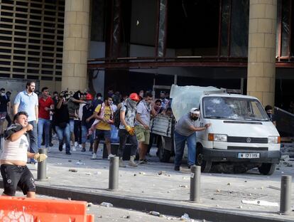 Aún en estado de conmoción por esta explosión de una violencia sin igual en la historia del país, muchos libaneses piden cuentas a una clase política cuya negligencia y corrupción denuncia. En la imagen, un grupo de manifestantes se protege escondiéndose detrás de una furgoneta.