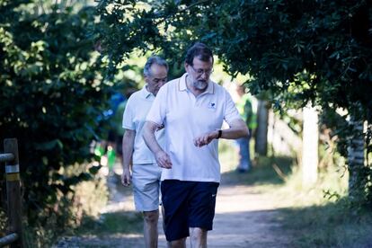 Mariano Rajoy camina con el presidente de la Autoridad Portuaria de Marín, José Benito Suárez (detrás), por la orilla del río Umia en el término pontevedrés de Ribadumia, en el comienzo de sus vacaciones de verano, el 2 de agosto de 2017.