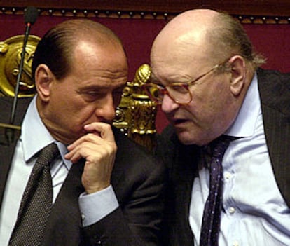 Renato Ruggiero conversa con Silvio Berlusconi durante un debate parlamentario.