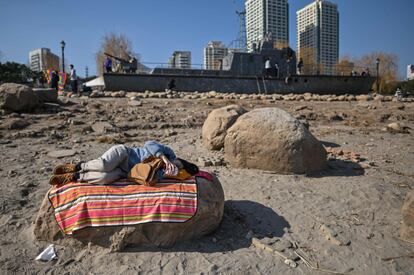 Una mujer descansa sobre una piedra, en un descampado de Wuhan. Las autoridades sanitarias de China han informado este miércoles de que se han registrado por primera vez dos casos de la nueva cepa británica del coronavirus en Pekín, la capital del país.