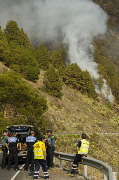 El detenido, que ha sido trasladado al cuartel de Los Llanos de Aridane, residía muy cerca de donde comenzaron las llamas, en el área rural de Jedey. En la imagen, un grupo de agentes en la posición de control de acceso a la carretera general ante la inminente llegada de las llamas del fuego.