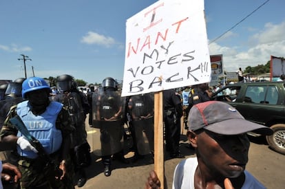 Un partidario del candidato presidencial Tubman protesta ante la policía liberiana y los cascos azules en Monrovia