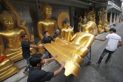 Trabajadores tailandeses trasladan una estatua de Buda de una tienda en Bangkok con motivo de los preparativos de la próxima próxima cuaresma budista.