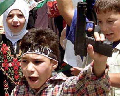 Un niño palestino empuña una pistola de juguete en el funeral de una víctima del conflicto israelo-palestino.