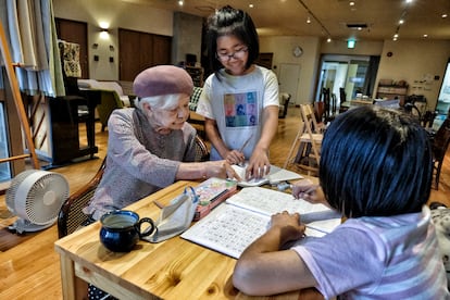 At 92, former teacher Kaneko helps two young girls with their homework. 