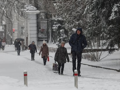 Un grupo de personas camina por una céntrica calle de Kiev en mitad de una nevada, este lunes.
