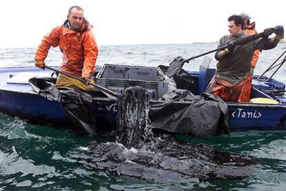 Varios <i>percebeiros</i> recogen restos de fuel cerca de la bocana de la ría de Arousa casi un mes después de la catástrofe del <i>Prestige.</i>