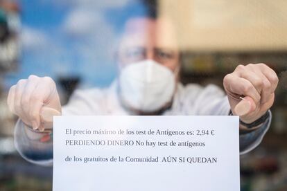 Un farmacéutico coloca un cartel en el que indica que pierden dinero con el nuevo precio de los test de antígenos en una farmacia de Madrid.