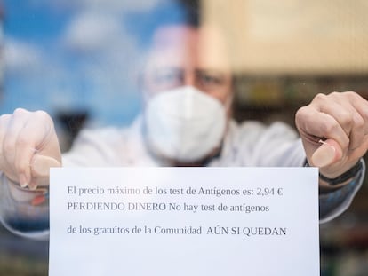 Un farmacéutico coloca un cartel en el que indica que pierden dinero con el nuevo precio de los test de antígenos en una farmacia de Madrid.