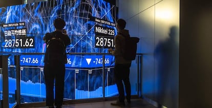 Dos ciudadanos observan un panel de cotizaciones en Tokio.
