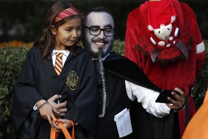 Un hombre disfrazado de vampiro se hace un 'selfie' con una niña vestida de Hermione, de 'Harry Potter', mientras esperan para reunirse con el presidente y su esposa.