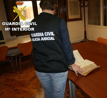 Una agente de la Guardia Civil muestra el libro sustraído y recuperado por el Archivo Histórico Diocesano de Teruel.