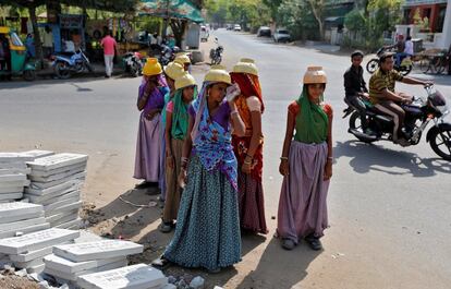 Sarta Kalara (C), a construction worker, stands among other female workers in Ahmedabad, India, April 20, 2016. Kalara says she has no option but to tether her daughter Shivani to a stone despite her crying, while she and her husband work for 250 rupees ($3.8) each a shift digging holes for electricity cables in the city of Ahmedabad. There are about 40 million construction workers in India, at least one in five of them women, and the majority poor migrants who shift from site to site, building infrastructure for India's booming cities. Across the country it is not uncommon to see young children rolling in the sand and mud as their parents carry bricks or dig for new roads or luxury houses. REUTERS/Amit Dave       SEARCH "TIED TODDLER" FOR THIS STORY. SEARCH "THE WIDER IMAGE" FOR ALL STORIES       TPX IMAGES OF THE DAY