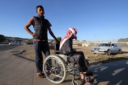 Dos refugiados sirios esperan la llegada de un taxi que les llevará al puerto.