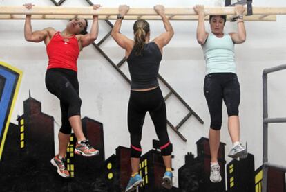 Three women hoping to become firefighters train in a gym, in order to pass the difficult physical tests.