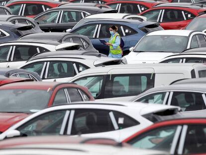 Una trabajadora de Ford camina entre automóviles aparcados en el exterior de la planta en Almussafes (Valencia).
 