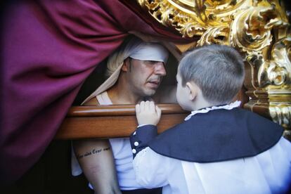 Un niño habla con un costalero de la Hermandad del Cristo del Cachorro de Sevilla.