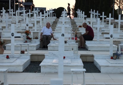 Loukas Alexandrou, de 90 años, y su hijo, sentados sobre la tumba de su otro hijo, muerto en la invasión turca de Chipre de 1974, en el cementerio militar de Tymvos Makedonitissas, en Nicosia.