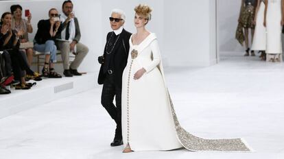 Lagerfeld, con una modelo vestida de novia al final del desfile de alta costura otoño-invierno 2014/2015 de Chanel, en julio de 2015