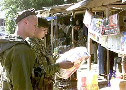 Soldados rusos leen un periódico ayer en un pequeño mercado de Grozni.