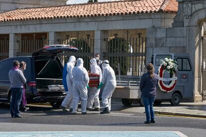 Operarios con trajes de protección portan un ataúd en el cementerio de Ávila este viernes para su entierro, ante la mirada de los pocos familiares que han podido asistir por las limitaciones establecidas debido al estado de alarma.