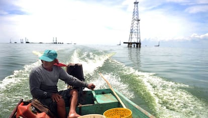 Un pescador navega frente a una torre petrolera en el lago Maracaibo.