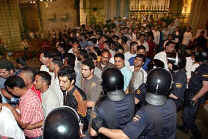 Agentes antidisturbios, junto al altar de la catedral de Barcelona, dirigen a los inmigrantes hacia la salida del templo.