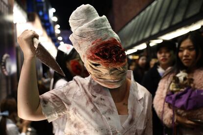 Una mujer caracterizada para Halloween con un cuchillo y la cabeza vendada participa en un desfile en Seúl, el 27 de octubre de 2017.