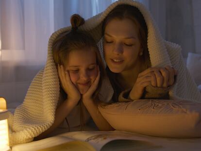 Una madre lee con su hija en la cama.