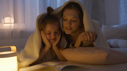 Una madre lee con su hija en la cama.