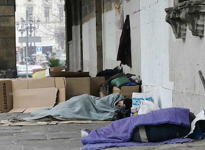 Varias personas sin hogar protegiéndose del frío con cartones y mantas  en pleno centro de Bilbao.