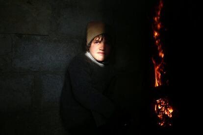 Un muchacho se coloca cerca de un fuego en el vecindario rebelde de Douma, en Damasco (Siria).
