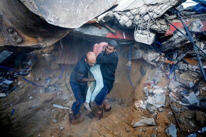 Two Palestinian men remove the body of a victim of Israeli bombings from under the rubble in Deir Al-Balah, Gaza Strip, on Sunday.