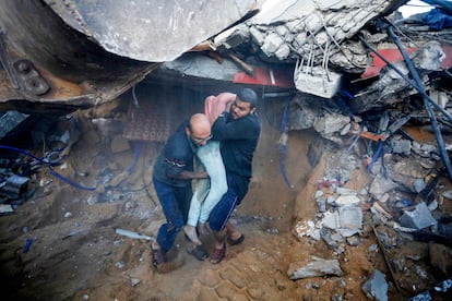 Dos civiles rescatan el cuerpo de un joven entre los escombros de una casa destruida tras un ataque israelí en la ciudad de Deir Al-Balah, en el centro de la franja de Gaza, este domingo.