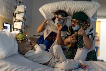 Luis Escuder, de dos años y medio, juega con unas payasas de la ONG Pallapupas en su habitación del Sant Joan de Déu Pediatric Cancer Center.