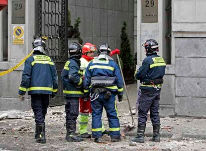 Los bomberos de Madrid retiran los cascotes caídos a la calle desde la cornisa.