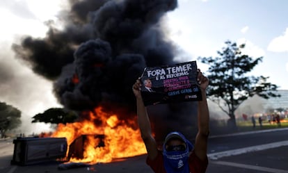 Manifestante com cartaz contra o presidente Temer, diante de uma barricada em Brasília. 