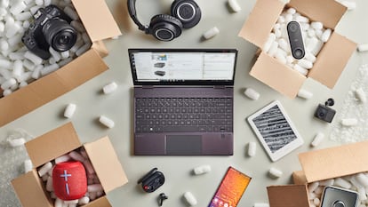 Un ordenador, una tablet, un móvil y cajas abiertas encima de una mesa.