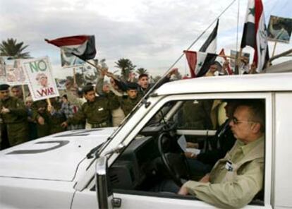 Inspectores de la ONU pasan junto a una manifestación de iraquíes contra la guerra, ayer en Bagdad.