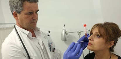 El m&eacute;dico Ruiz Maroto toma una muestra a una mujer para diagnosticar la gripe.